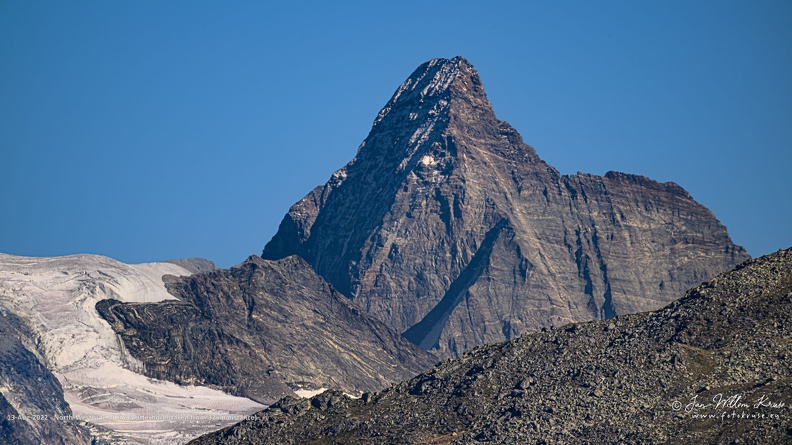 The Matterhorn, a mountain shaped like an Egyptian pyramid, is 4478 metres high (14692 ft) located at the border between Switserland and Italy nearby the Swiss town of Zermatt in the Mattertal valley in the canton of Valais.
The Matterhorn has four faces nearly facing the four compass points. Three of them (north, east and west) are on the Swiss side of the border and one of them (south) is on the Italian side of the border in the Valtournenche valley. From the area of Zermatt the east and north faces are visible.
The Matterhorn's faces are steep, and only small patches of snow and ice cling to them; regular avalanches send the snow down to accumulate on the glaciers at the base of each face. The mountain has two distinct summits, situated at either end of a 100-metre-long (330 ft) exposed rocky crest which forms the Italian/Swiss border.
Millions of years ago, it was part of the African continent. Nowadays it is one of the most famous mountains in the world and is the best-known landmark in Switzerland. North-West side of the Matterhorn (taken from 32km distance)