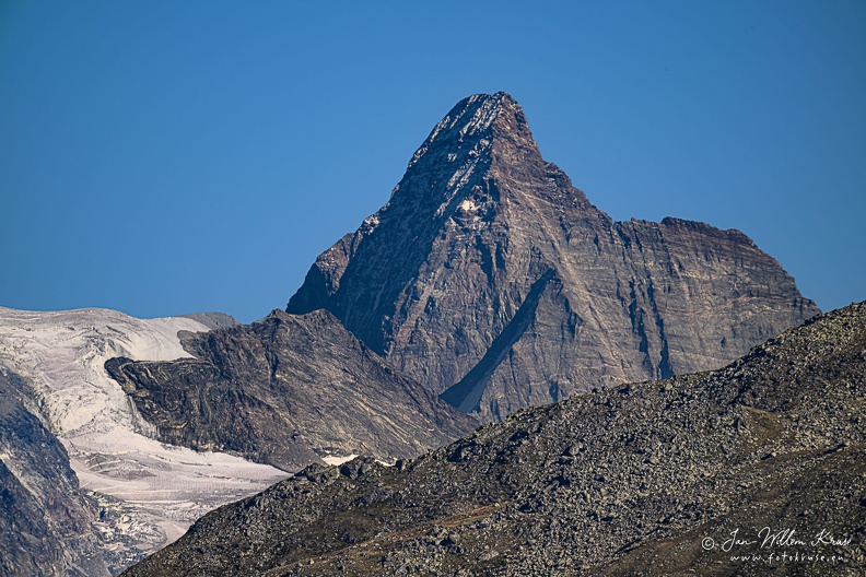 The Matterhorn, a mountain shaped like an Egyptian pyramid, is 4478 metres high (14692 ft) located at the border between Switserland and Italy nearby the Swiss town of Zermatt in the Mattertal valley in the canton of Valais.
The Matterhorn has four faces nearly facing the four compass points. Three of them (north, east and west) are on the Swiss side of the border and one of them (south) is on the Italian side of the border in the Valtournenche valley. From the area of Zermatt the east and north faces are visible.
The Matterhorn's faces are steep, and only small patches of snow and ice cling to them; regular avalanches send the snow down to accumulate on the glaciers at the base of each face. The mountain has two distinct summits, situated at either end of a 100-metre-long (330 ft) exposed rocky crest which forms the Italian/Swiss border.
Millions of years ago, it was part of the African continent. Nowadays it is one of the most famous mountains in the world and is the best-known landmark in Switzerland. North-West side of the Matterhorn (taken from 32km distance)