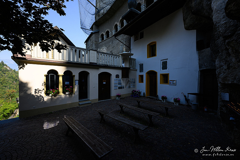 Small courtyard with benches and white buildings tucked beneath a rock overhang at Longeborgne.