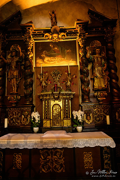 Ornate altar with a central Pietà, carved figures, gilded details and flowers at Longeborgne.