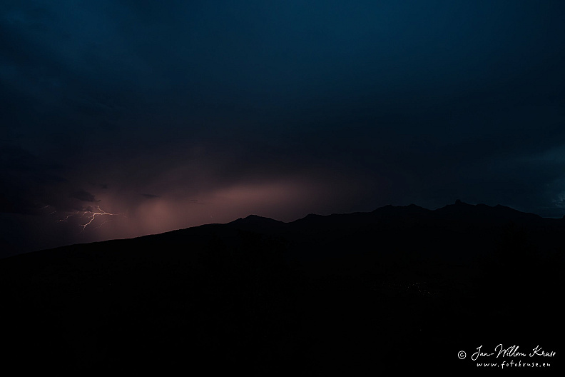 Lightning bolt beneath dark storm clouds over La Maya and nearby mountain ridges.