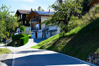 Residential Lane in the Valais Alps (12 visits) A quiet paved lane climbs between chalet-style homes on a sunny, wooded Valais hillside. Residential Lane in the Valais Alps