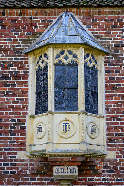 Ornate projecting 1554 oriel window with leaded stained glass on the brick north facade of Klooster Ter Apel.